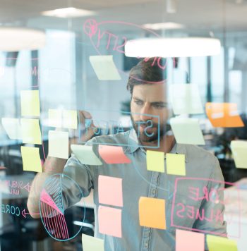 Young businessman writing on glass while planning